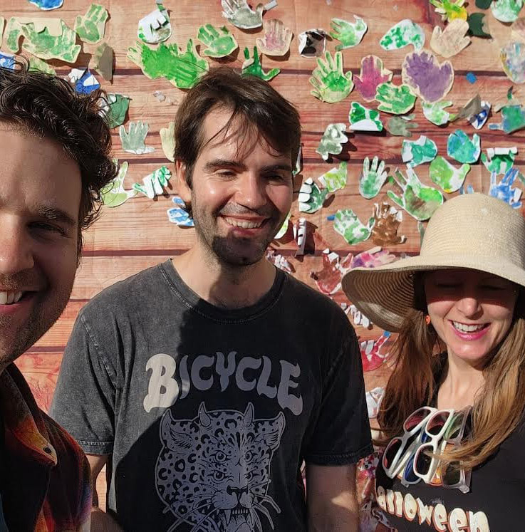 three friends, one is taking a selfie. all are smiling.