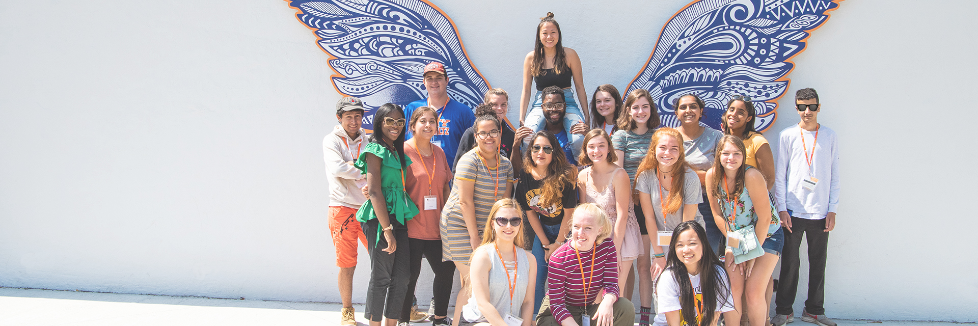 students standing in front of wing mural on wall