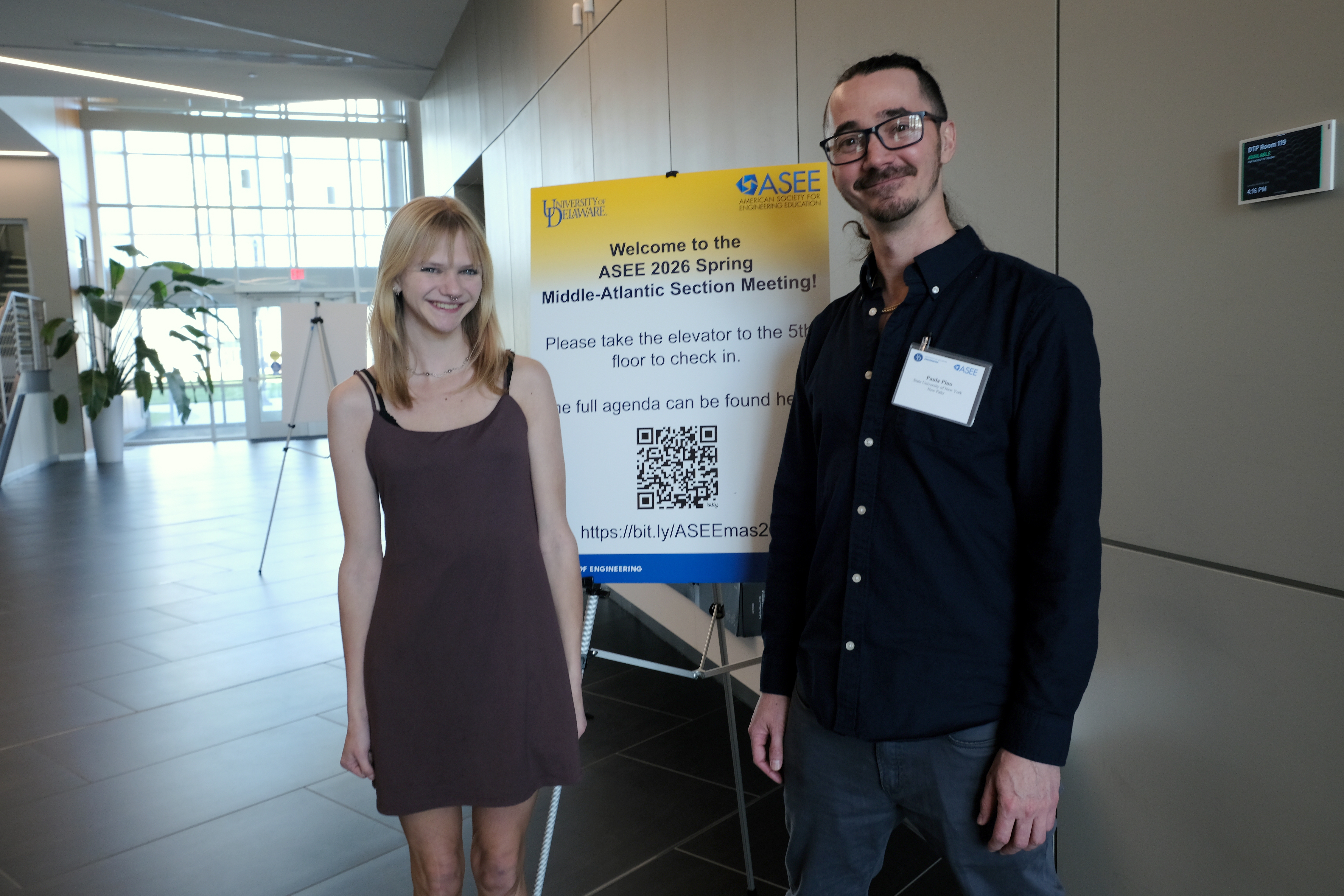 Two students pose in front of conference sign.