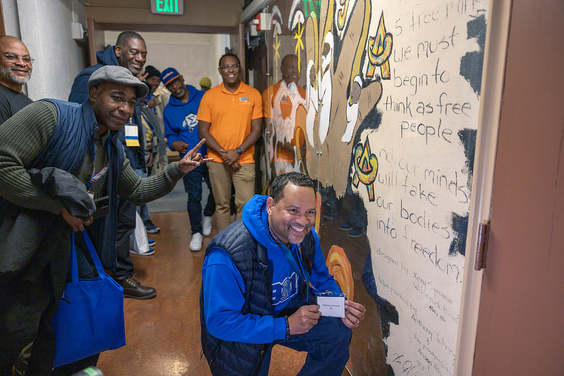 Alumni look at murals in Shango Hall.