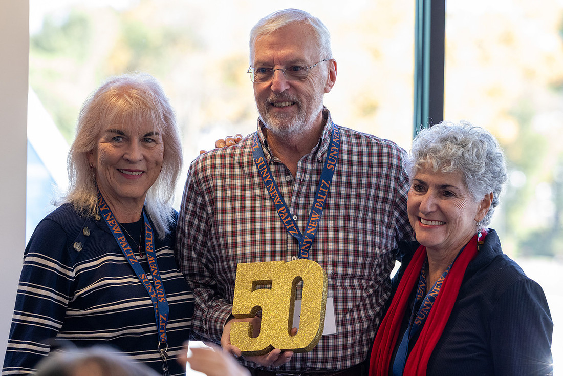 Folks pose around a sign that says 50.